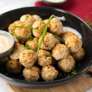 Keto Chicken Cheddar Meatballs in a dark bowl topped with chives