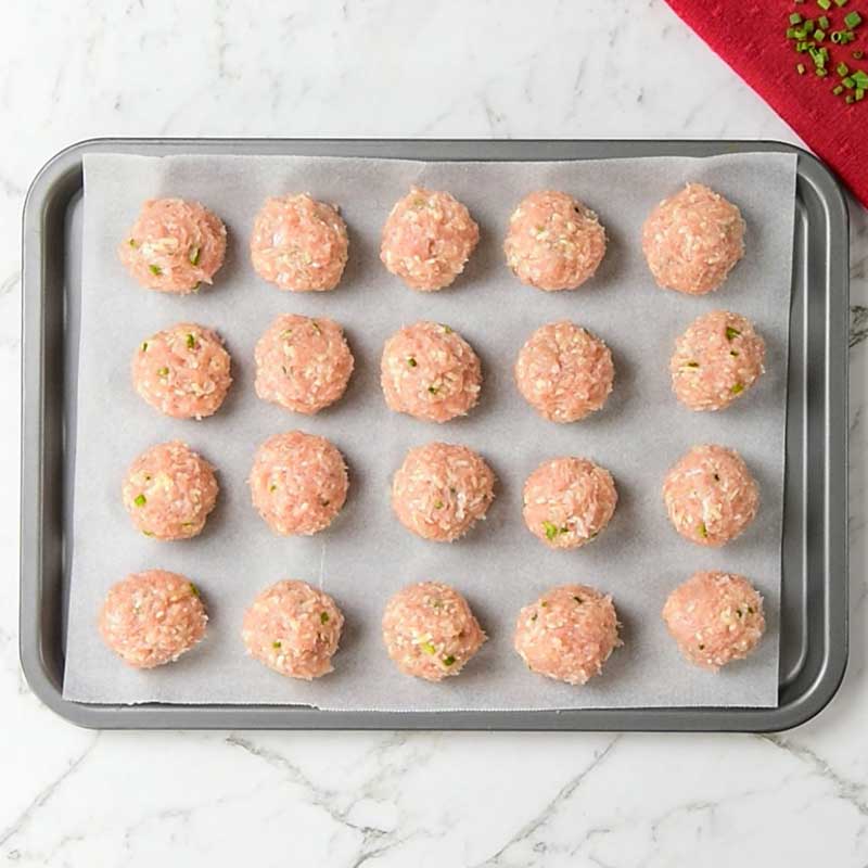 Keto Chicken Cheddar Meatballs Ingredients - raw meatballs on a lined baking tray