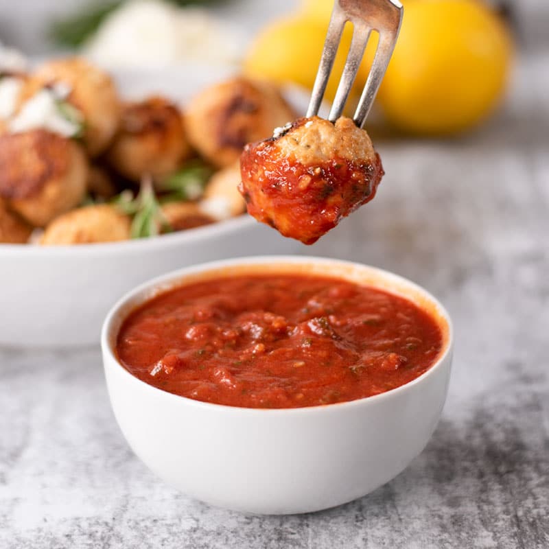 Keto Chicken Feta Meatball being dipped into Low Carb Marinara Sauce