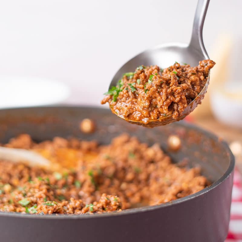 Keto Bolognese Sauce being ladled out of a saucepan