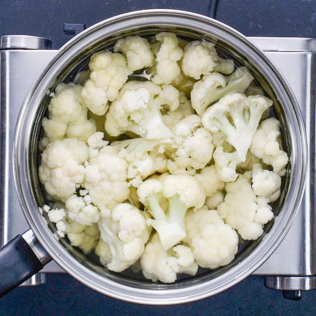 Cauliflower florets simmering in a saucepan of water