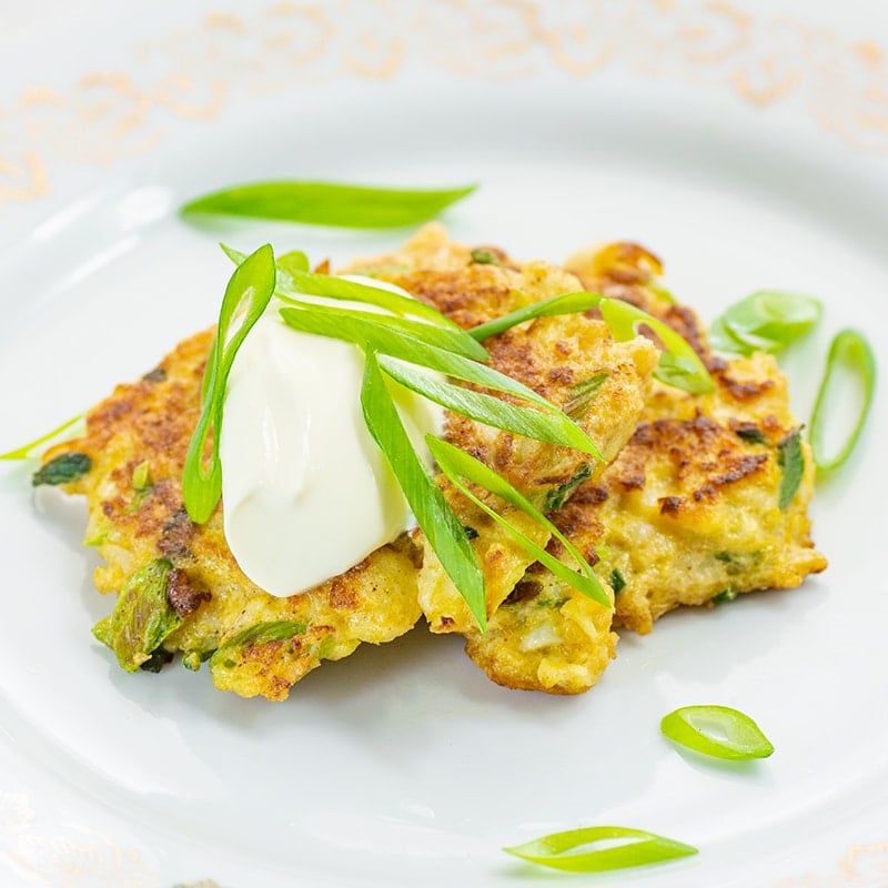 Keto Cauliflower Fritter on a plate topped with scallions and sour cream