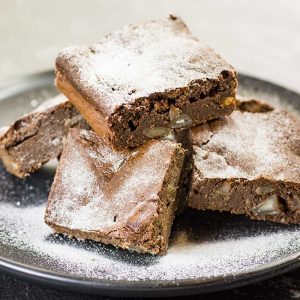 Keto Chocolate Macadamia Brownies on a plate covered with icing sweetener