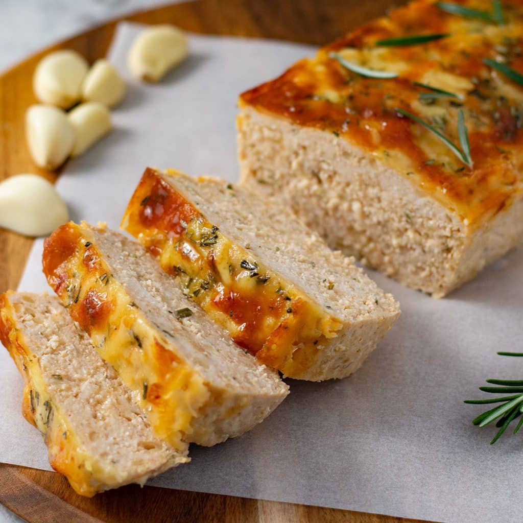 Keto cheesy chicken meatloaf sliced on baking paper.