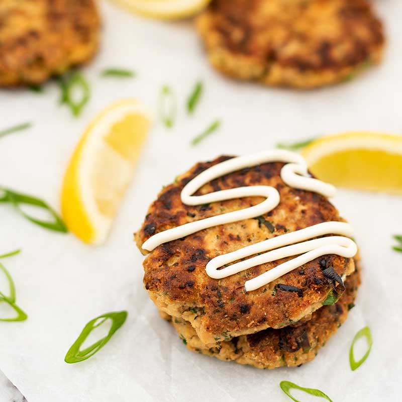 Salmon fish cakes on a plate with sauce.