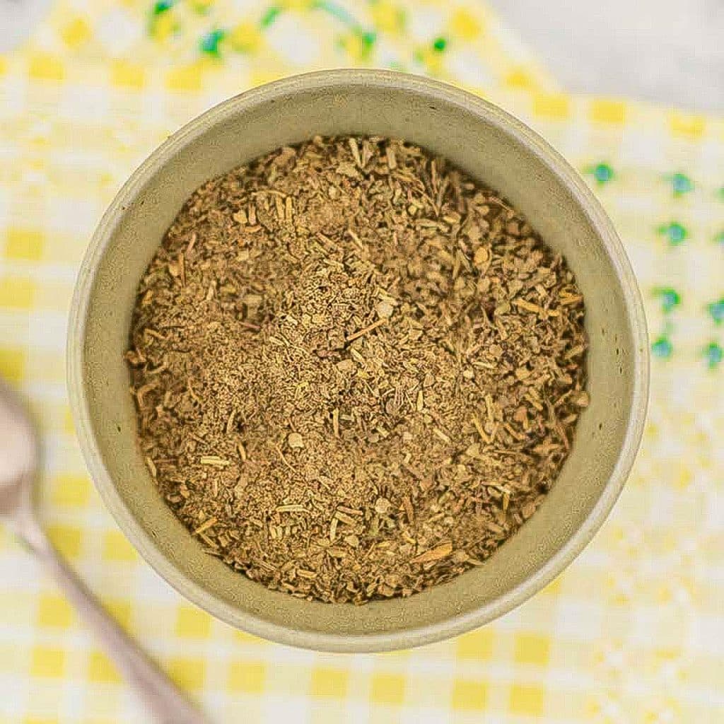 Keto poultry seasoning in a bowl on a yellow matt on a table.
