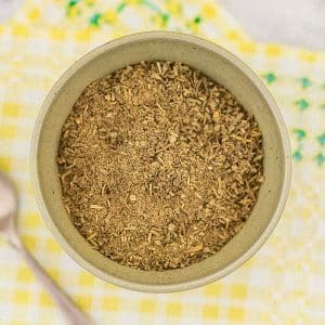 Keto poultry seasoning in a bowl on a yellow matt on a table.