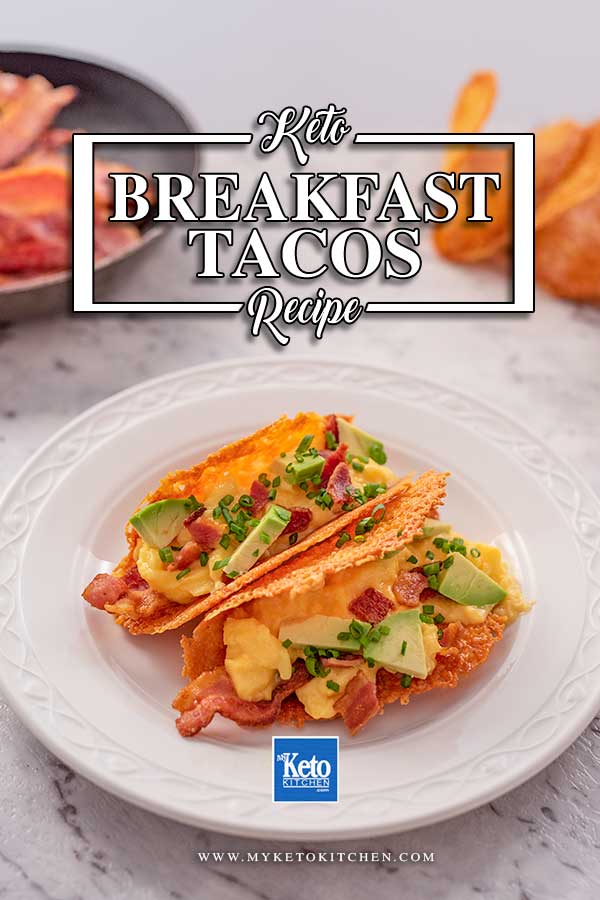 Imago shows two keto breakfast tacos on a white plate. The tacos are filled with bacon, scrambled eggs, avocado and chives.