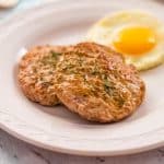 Keto breakfast sausage with an egg on a white plate.