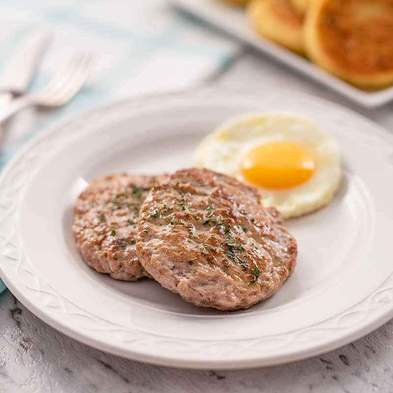 Image shows two keto breakfast sausage patties with a fried egg on a white plate