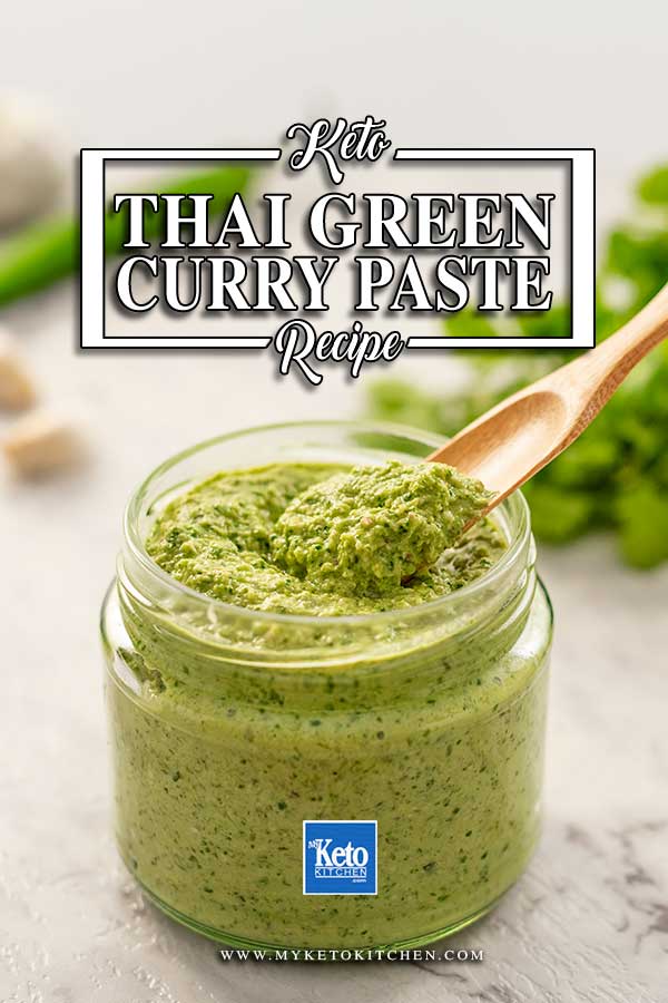 Image shows a wooden scoop filled with low carb thai green curry paste, the jar of curry paste is in the background