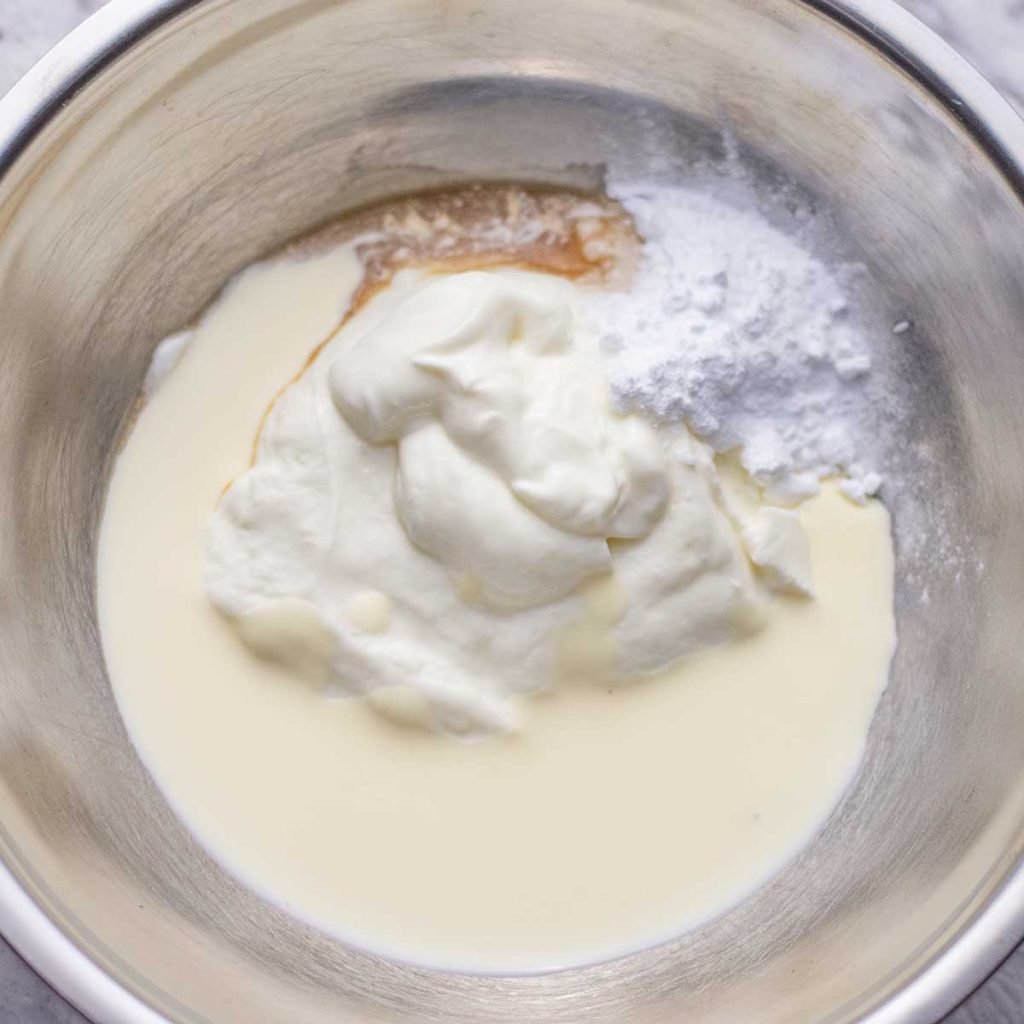 Ingredients for keto vanilla frozen yogurt in a silver mixing bowl