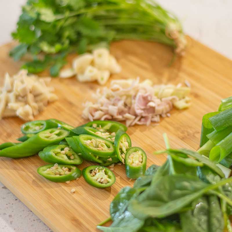 Image shows chopped ingredients for low carb thai curry paste on a wooden cutting board