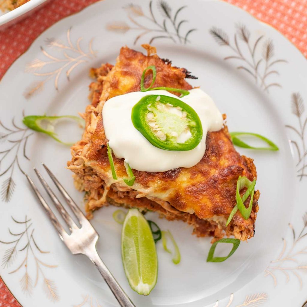 A slice of Keto Chicken Tamale Pie on a white plate with a dollop of sour cream on top