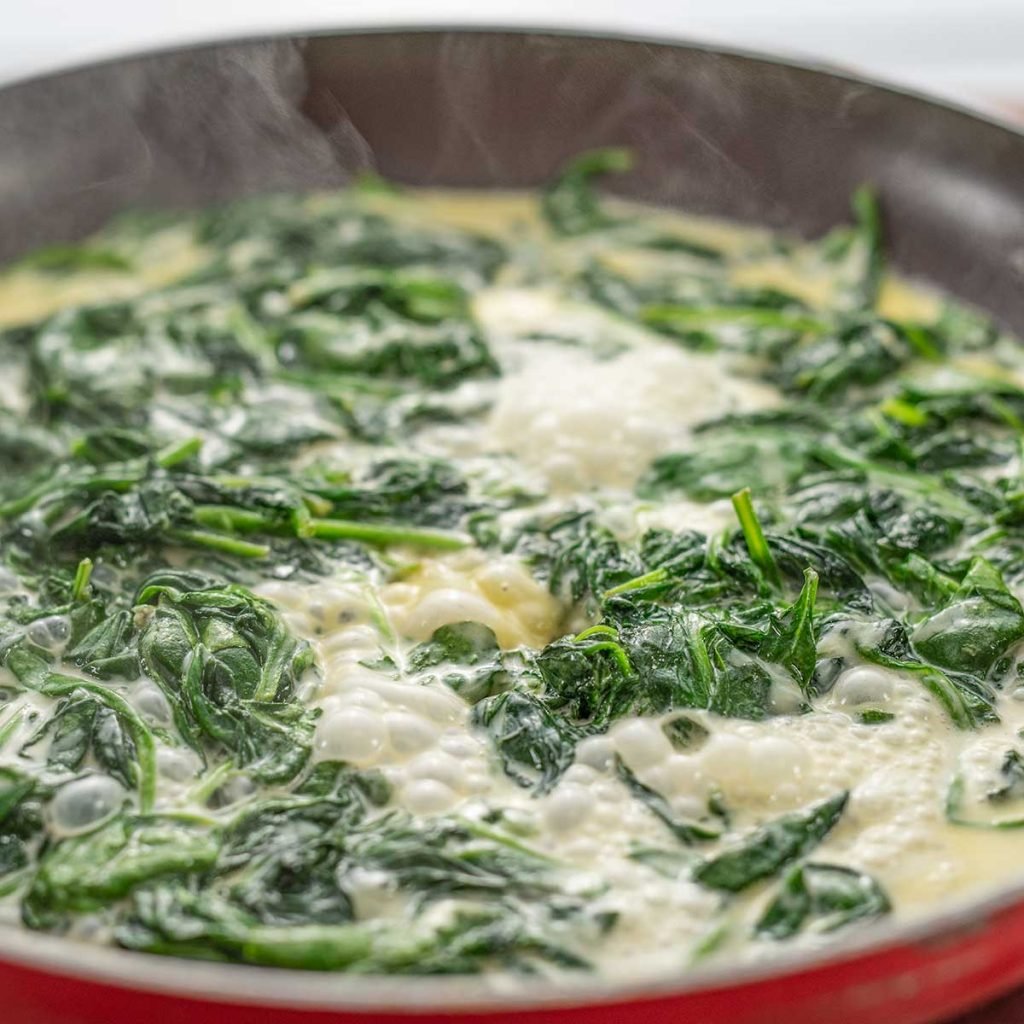 Keto Creamed Spinach simmering in a black frying pan