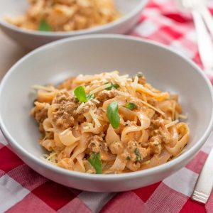 Keto Creamy Sausage Pasta in a grey bowl on a red checkered cloth