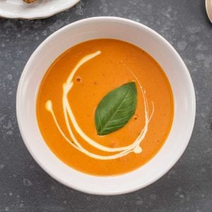 Keto Creamy Tomato Soup in a white bowl on a dark grey table