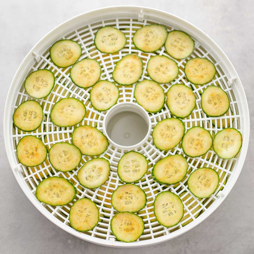 Raw cucumber chips on a dehydrator tray