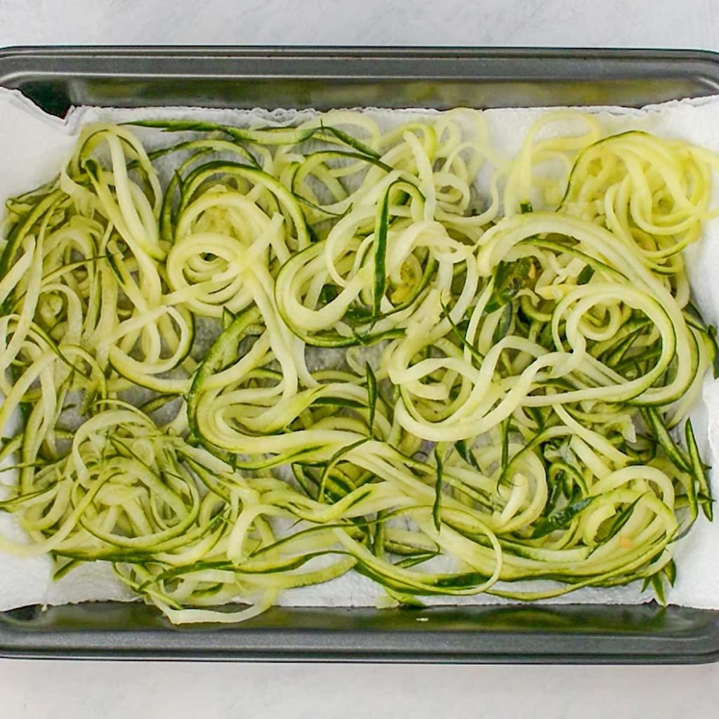 Cucumber noodles resting on a lined baking pan