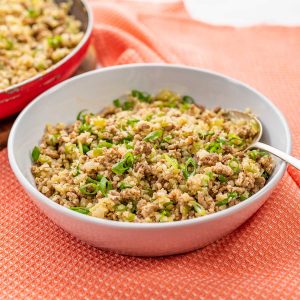 Keto Dirty Rice in a white bowl on an orange napkin