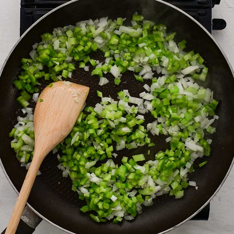 The ingredients for Keto Dirty Rice sauteing in a dark frying pan