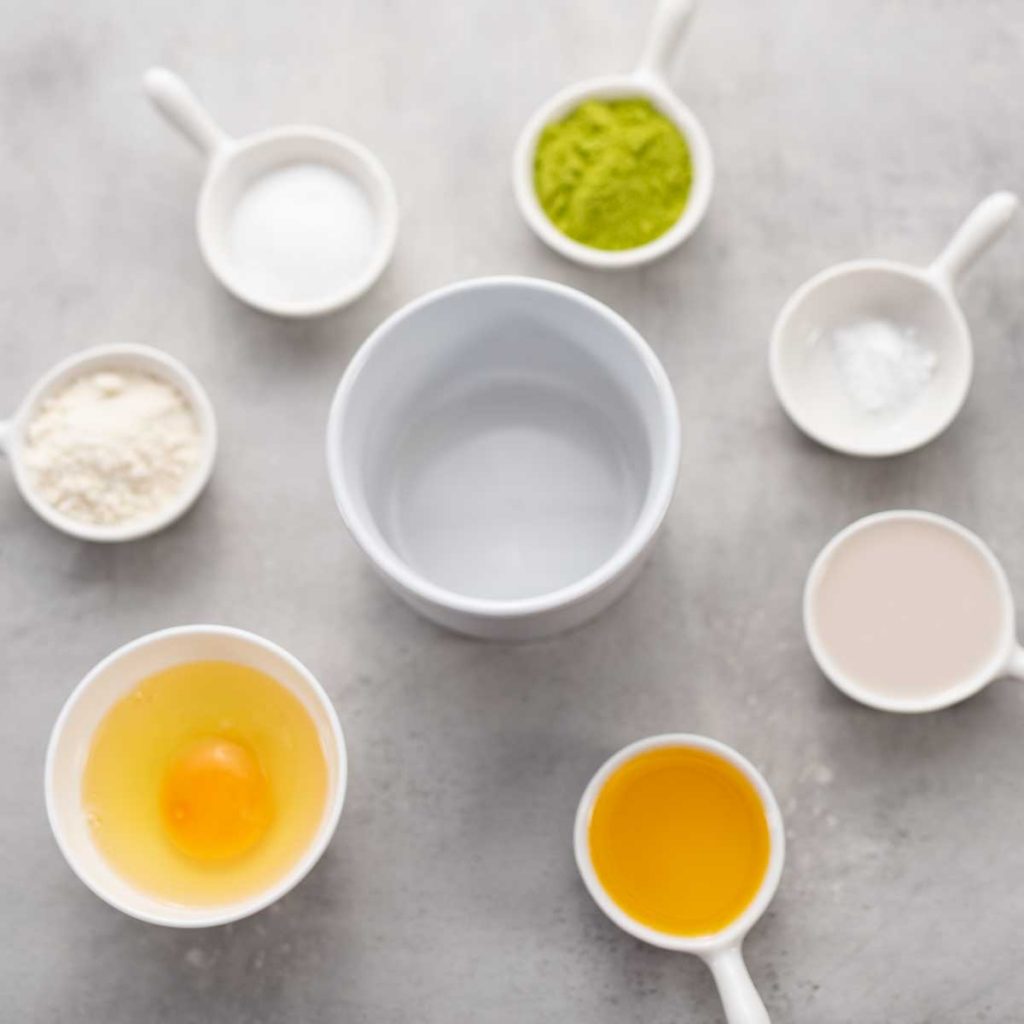 Ingredients for a keto matcha mug cake surrounding a white ramekin