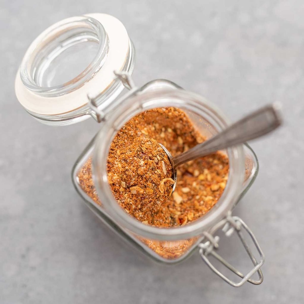 Montreal steak seasoning in a glass jar with a spoon sticking out