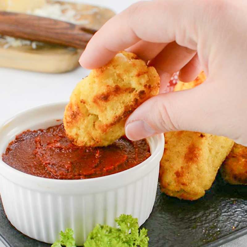 Keto Cauliflower tots being dipped in marinara sauce