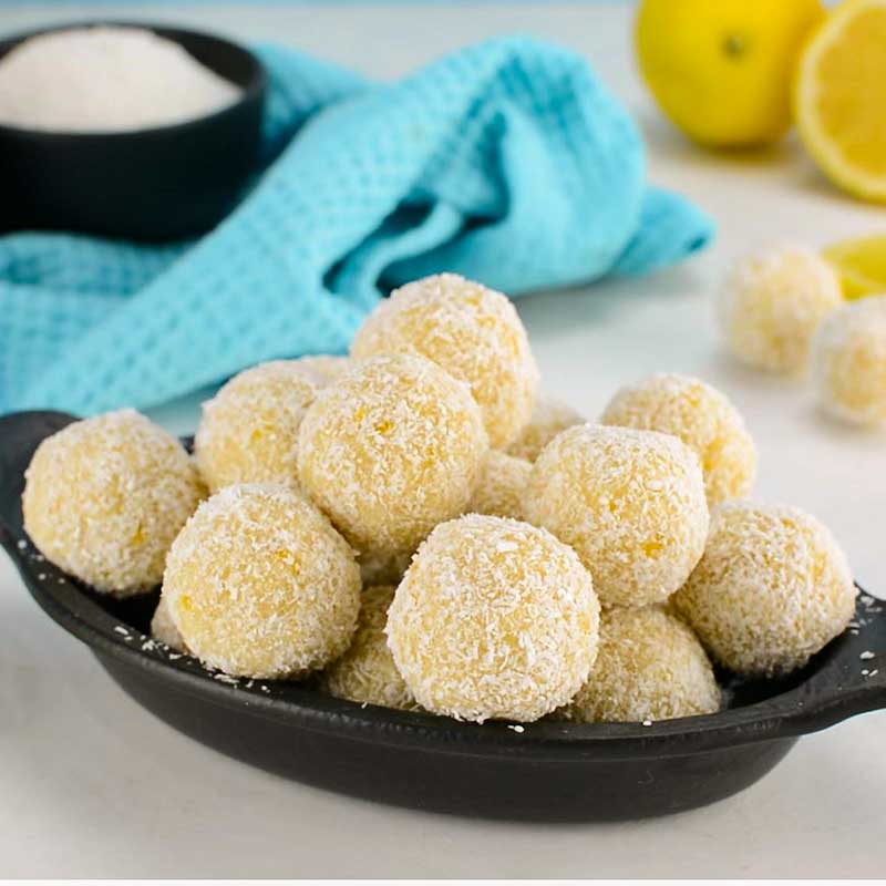 Lemon bliss balls on a black serving plate.