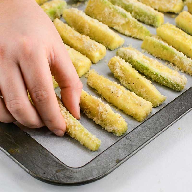 Raw Keto Zucchini Fries, breaded on a baking pan