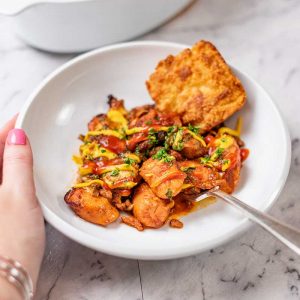 Keto Chili Cheese Dog Casserole in a bowl with a cheddar biscuit