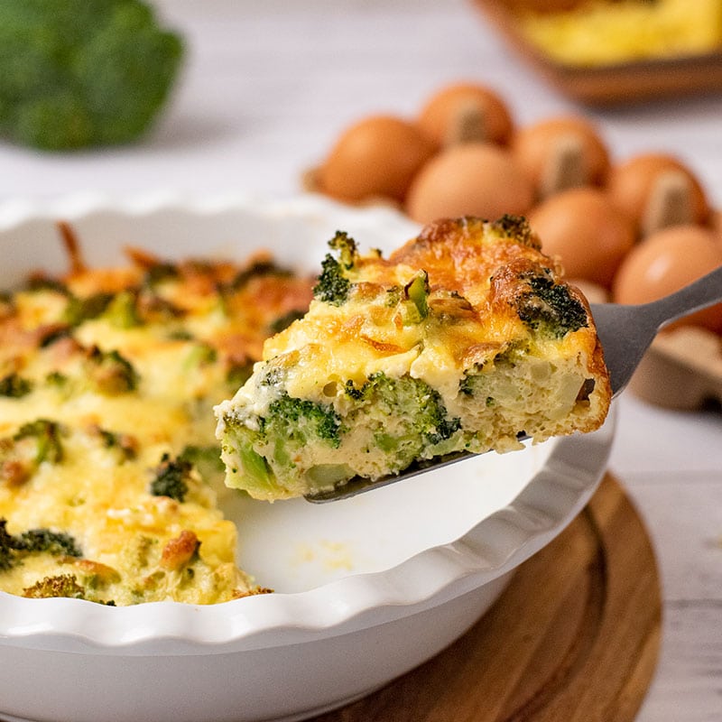 Keto Crustless Broccoli Quiche being lifted out of a pie dish