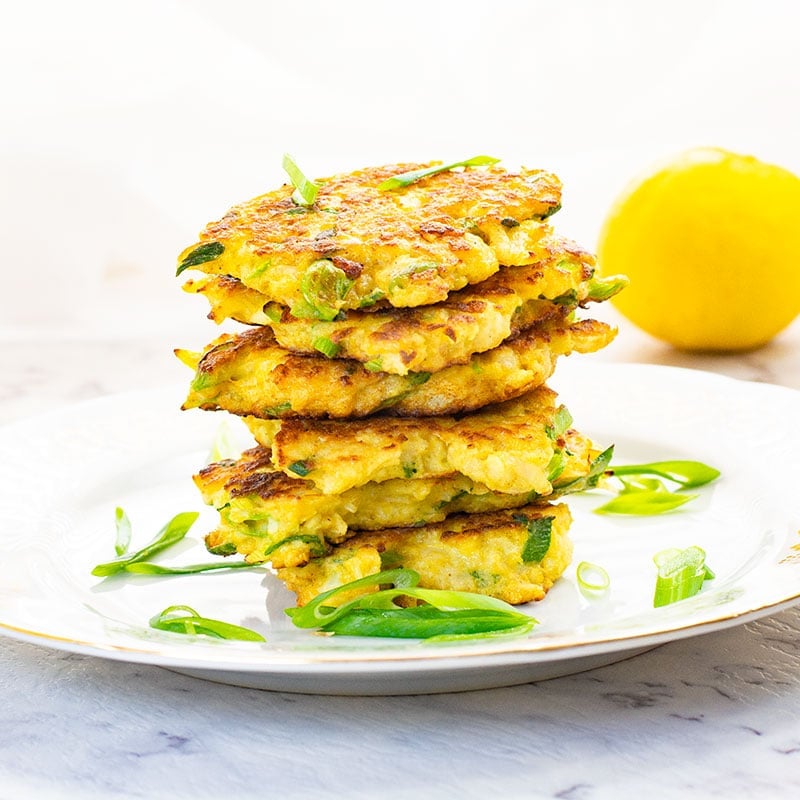 Cauliflower latkes stacked on a white plate.