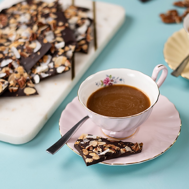 Keto Chocolate Sea Salt Bark on the saucer of a cup of coffee