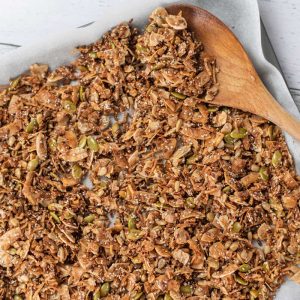 Keto Cinnamon Cereal on a baking sheet with a wooden spoon