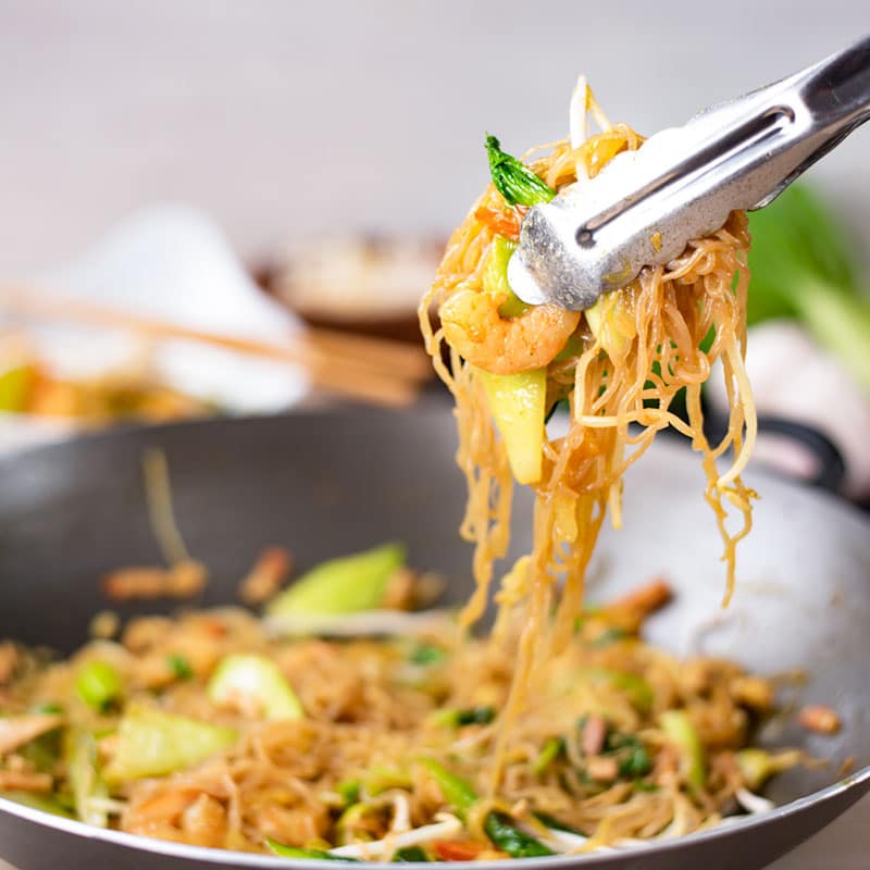 Keto Singapore Noodles being lifted my tongs from a wok