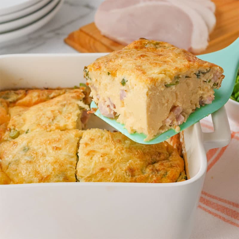 A slice of Keto Egg and Cream Cheese Bake being lifted from the baking dish.