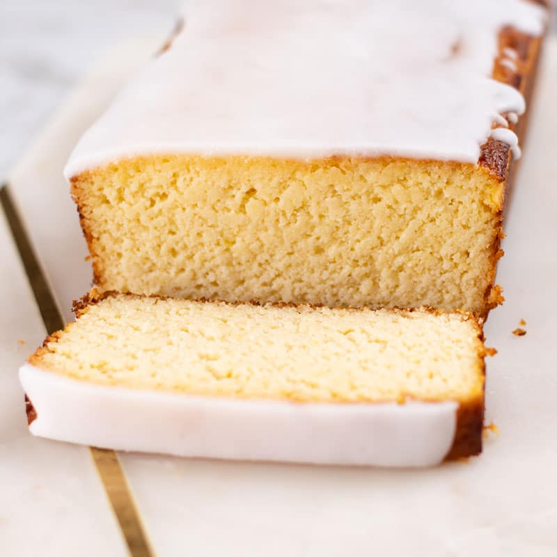 Keto Yogurt Cake on a marble slab with a slice cut to reveal the moist texture of the cake.