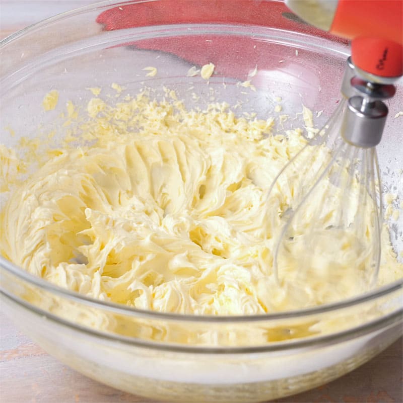 Keto Vanilla Buttercream Ingredients being whipped by a hand mixer with whisk attachment.