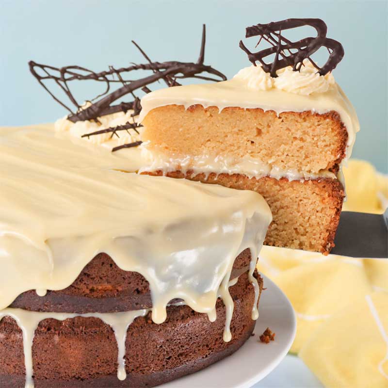 A slice of Keto Caramel Mud Cake being lifted from the whole cake.