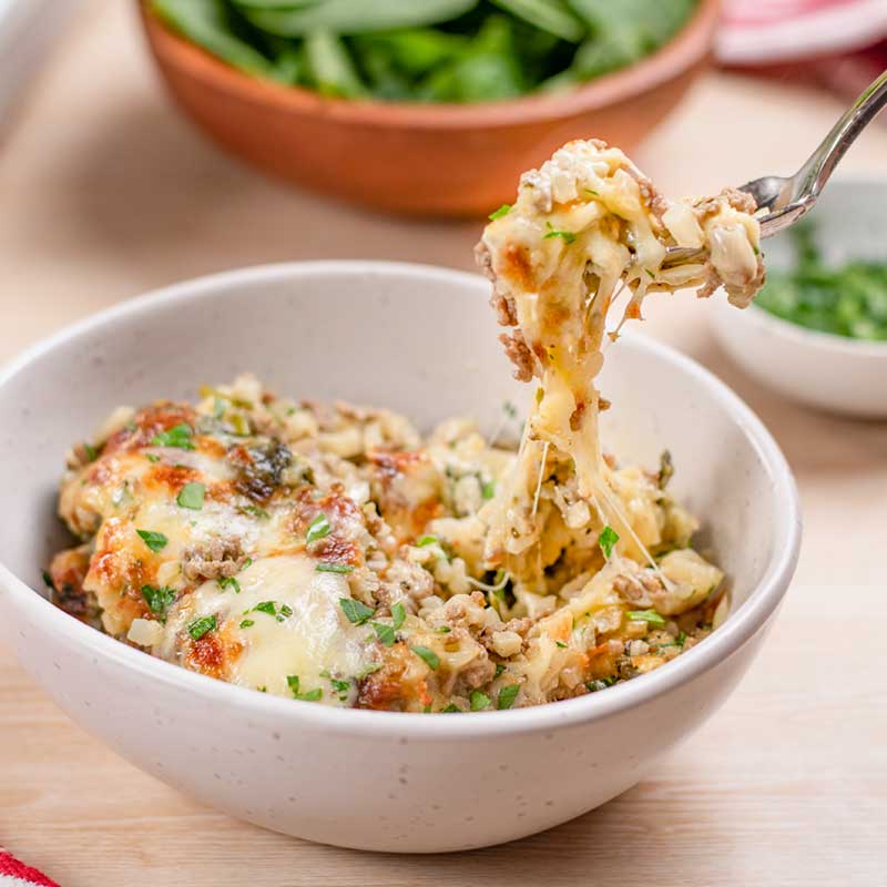Keto Cheesy Ground Beef Casserole served in a bowl with a fork removing a mouthful.