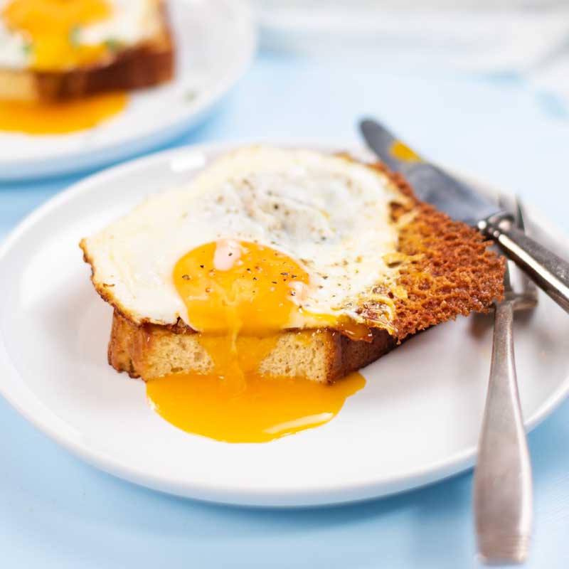 Keto Fried Eggs with Cheese on a plate with a slice removed and yolk pouring out.