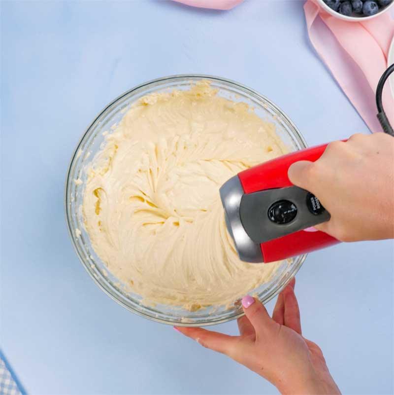 Keto Baked Vanilla Cheesecake Ingredients being mixed in a glass bowl.