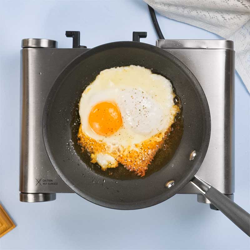 Keto Fried Eggs with Cheese cooking in a frying pan.