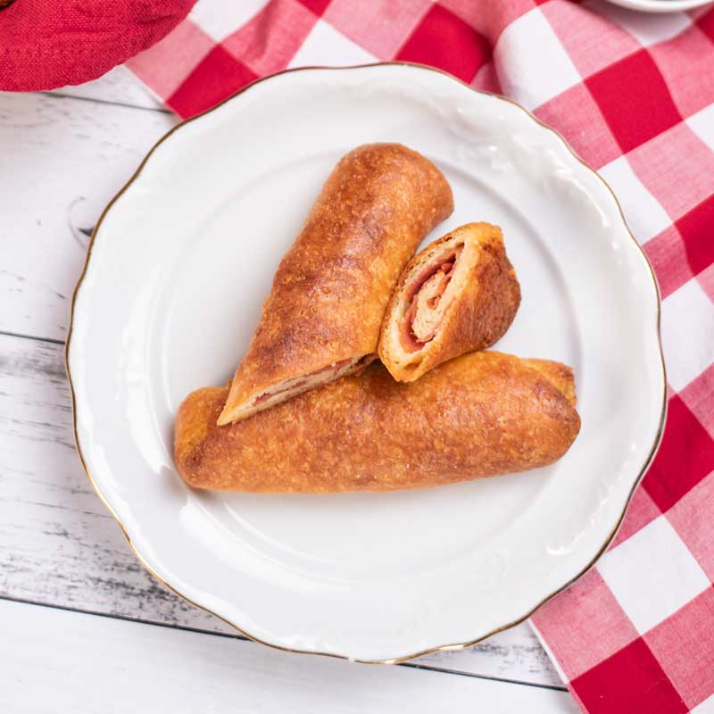 Keto Pepperoni Rolls on a plate with one cut open to show the swirl of pepperoni in the center.