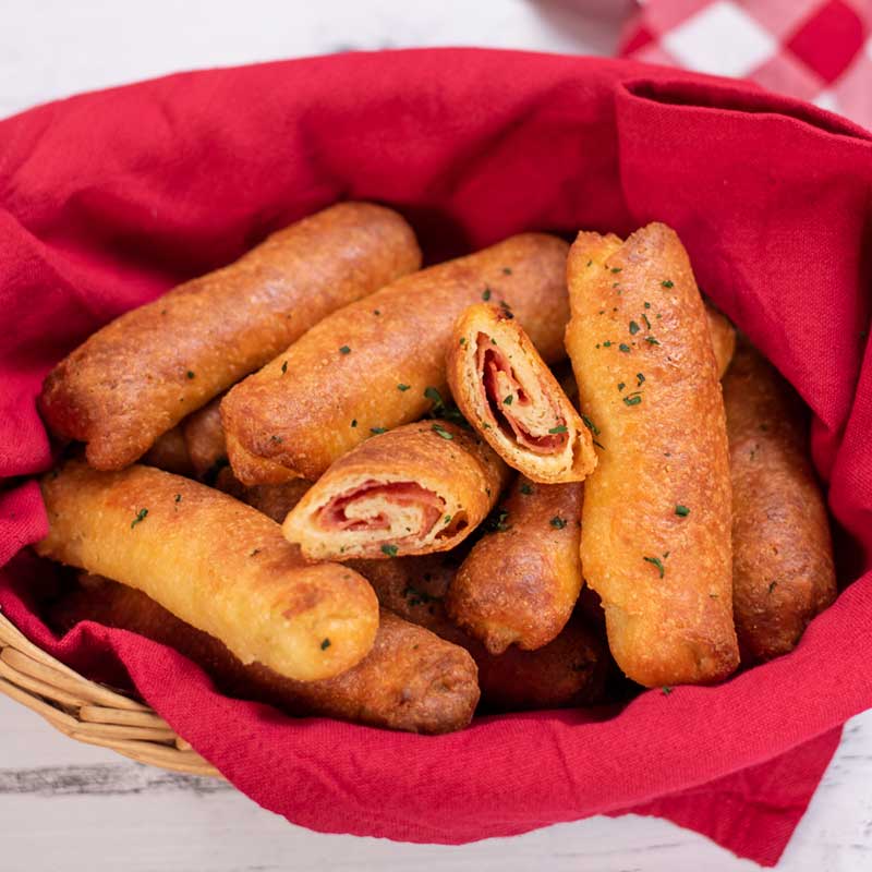 Keto Pepperoni Rolls in a basket with one cut open to show the swirl of pepperoni in the center.