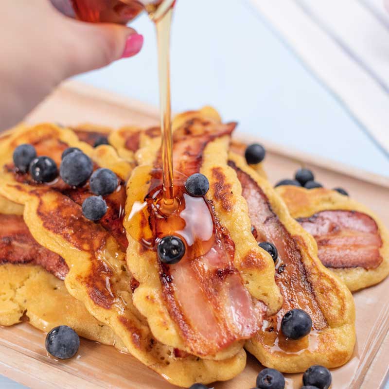 Keto Bacon Pancakes on a platter being drizzled with syrup.