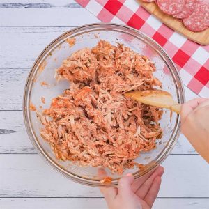 Keto Chicken Pizza Casserole Ingredients being mixed in a glass bowl.