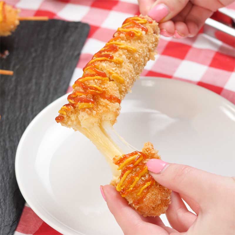 A Keto Korean Corn Dog being pulled open to show the melty cheese.