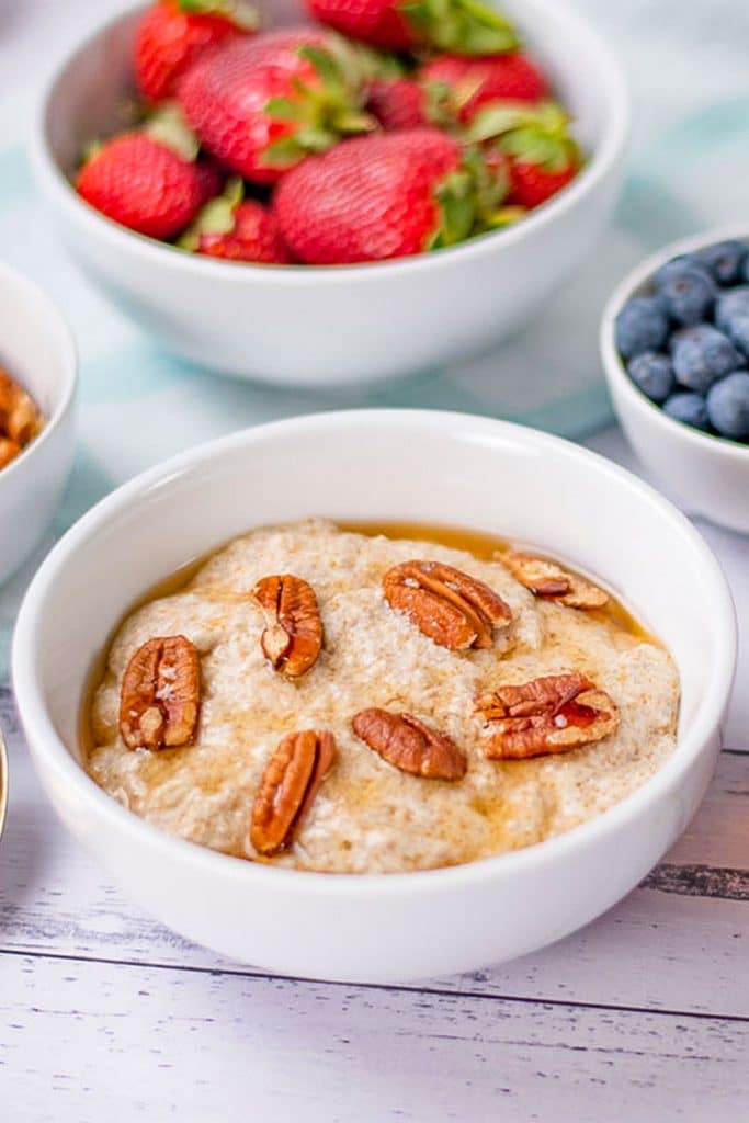 Keto porridge in a cereal bowl with strawberries and blueberries.